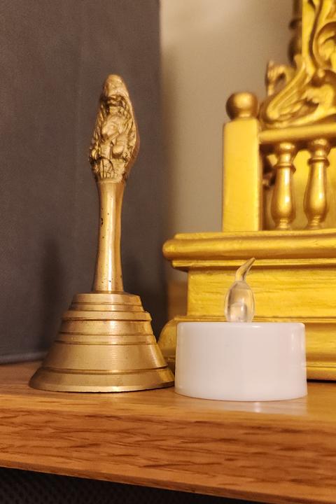 Bell and tea light with gold shrine in the background