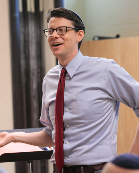 photograph of a man with glasses in a shirt and tie, teaching